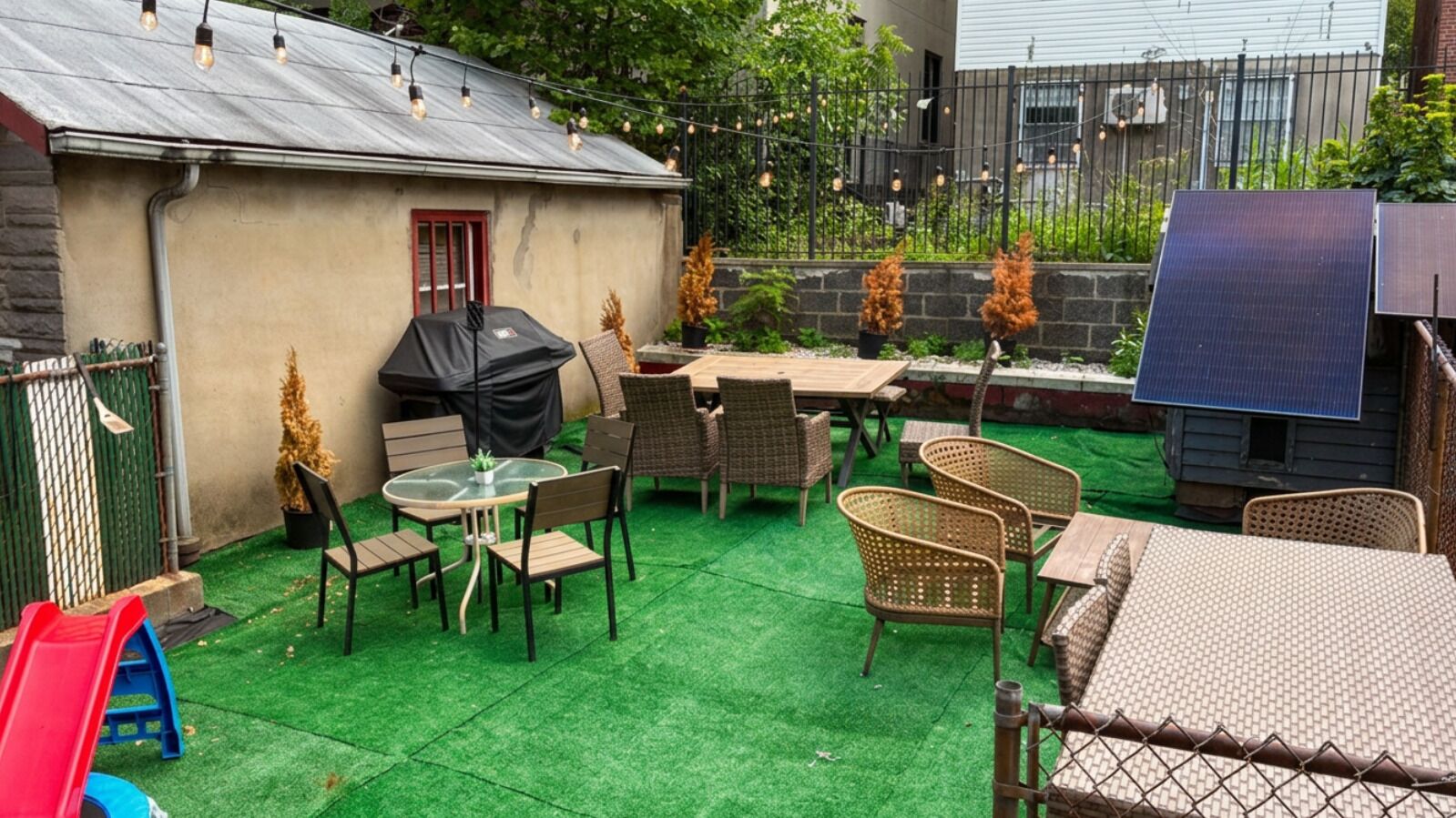 A backyard with a barbecue area, outdoor seating, and solar panels.