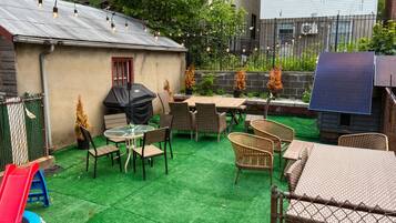 A backyard with a barbecue area, outdoor seating, and solar panels.