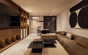 Ein modernes Wohnzimmer mit einer Eckcouch, einem Couchtisch, einem Esstisch mit Stühlen und einer eingebauten Holzhockerreie.