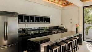 Une cuisine moderne dotée d’un îlot central, de tabourets de bar et d’un four encastré.