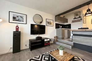 A modern living room with a flat-screen TV, a black entertainment unit, and a patterned rug. - ✨ Sea View Studio with Balcony – Deauville Boardwalk ✨ (Deauville)
