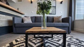 Un salon moderne avec un canapé gris, une table basse en bois et un tapis à motifs.