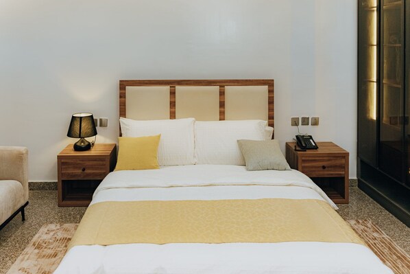 Une chambre d’hôtel avec un grand lit, deux tables de chevet, une lampe, un téléphone et une télévision.