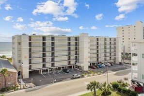 A multi-story hotel with a parking lot in front, located near a beach. - Direct Oceanfront Condo with Pool and Beach Views (North Myrtle Beach)