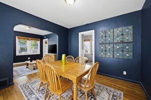 A dining room with a wooden table and chairs, a vase, and a blue wall with decorative tiles. - 3 Private Apts in Tremont - Perfect for Groups (Cleveland)