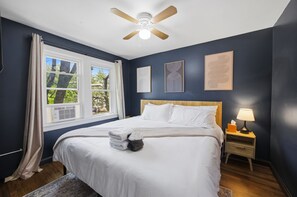 A hotel room with a bed, a ceiling fan, a nightstand with a lamp, and artwork on the walls. - 3 Private Apts in Tremont - Perfect for Groups (Cleveland)