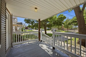 A covered porch with a white railing, a wooden post, and a view of a street with cars and trees. - Charming Tremont 3BR - Minutes to Downtown (Cleveland)