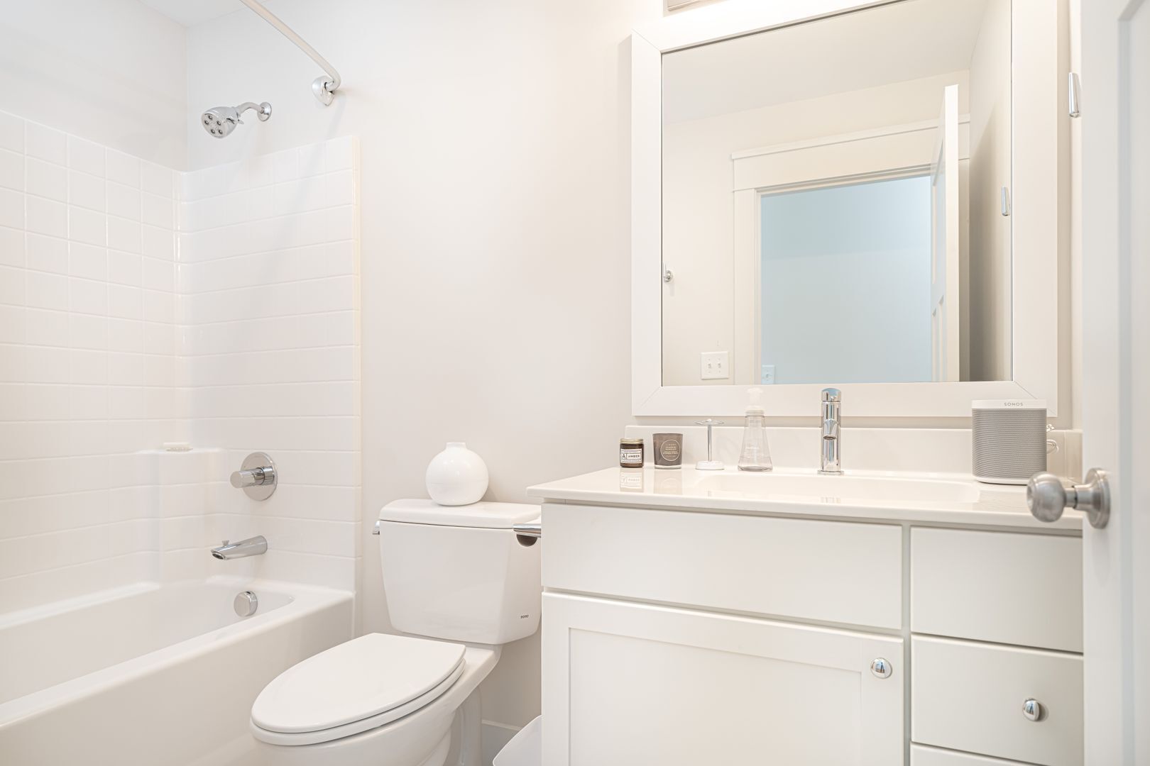 A modern bathroom with a bathtub, toilet, and vanity with a mirror and sink.