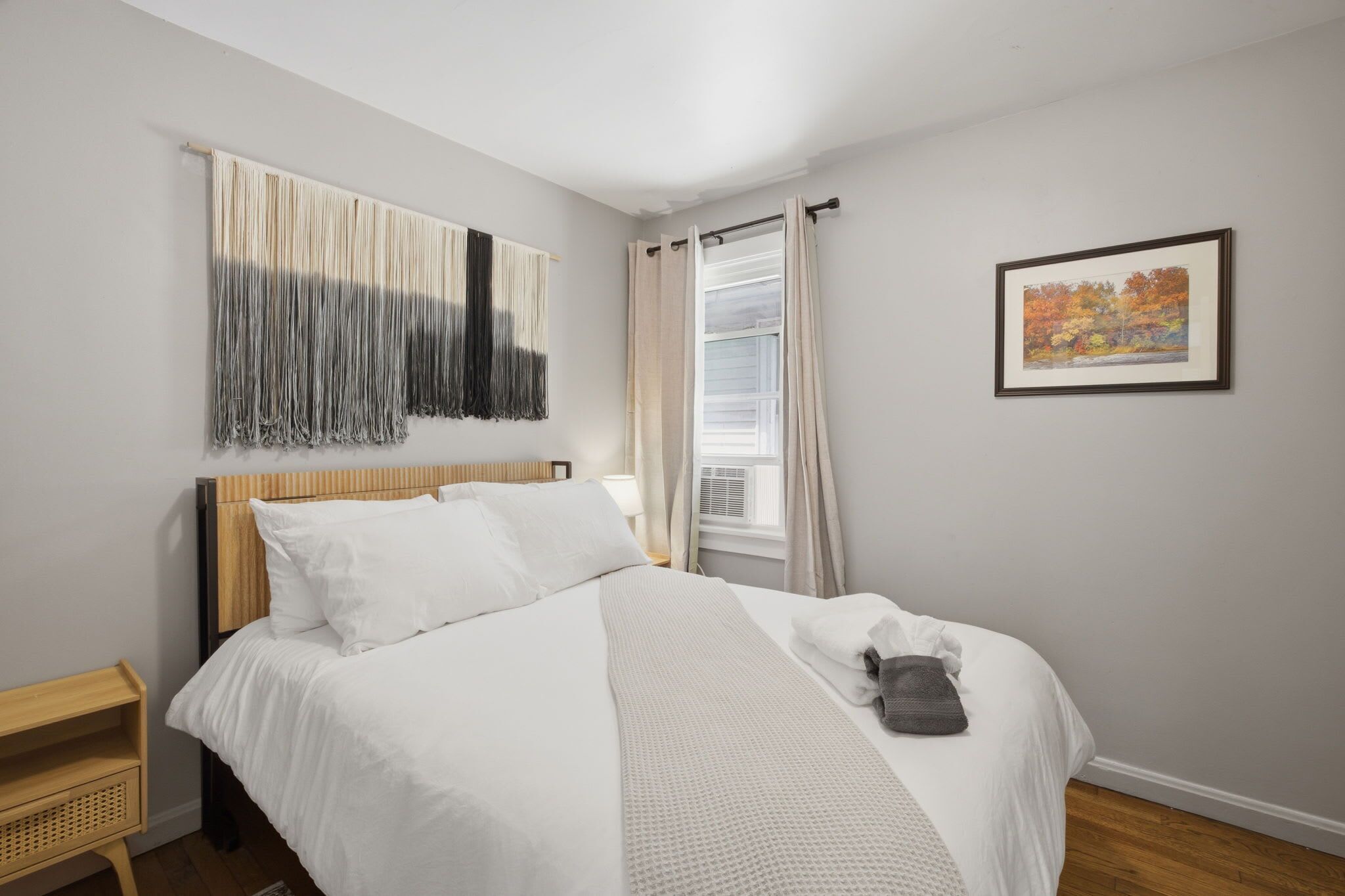 A neatly made bed with white linens, a headboard, and a blanket.