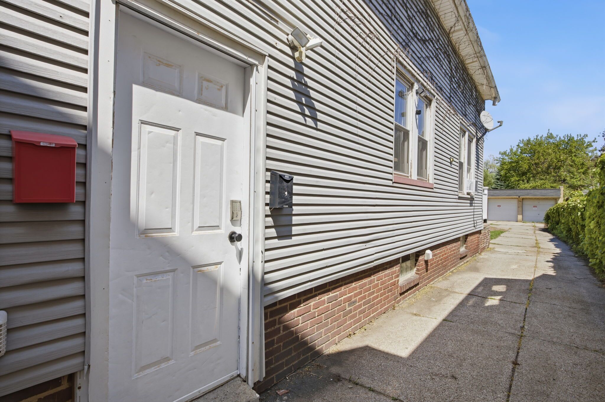 A residential building with a white garage door, a mailbox, and a brick foundation.