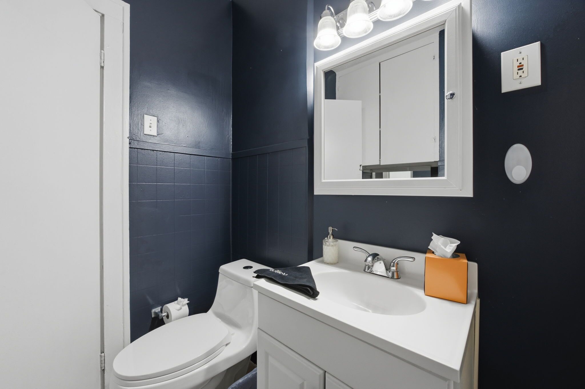Un baño con inodoro blanco, un lavabo con espejo y un perchero para toallas.