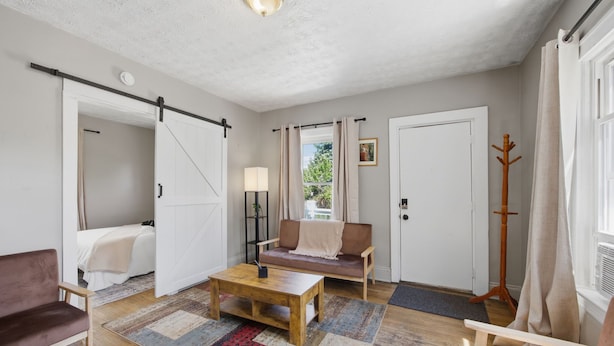 Une pièce comprenant un canapé, une table en bois, un porte-manteau et une porte coulissante.