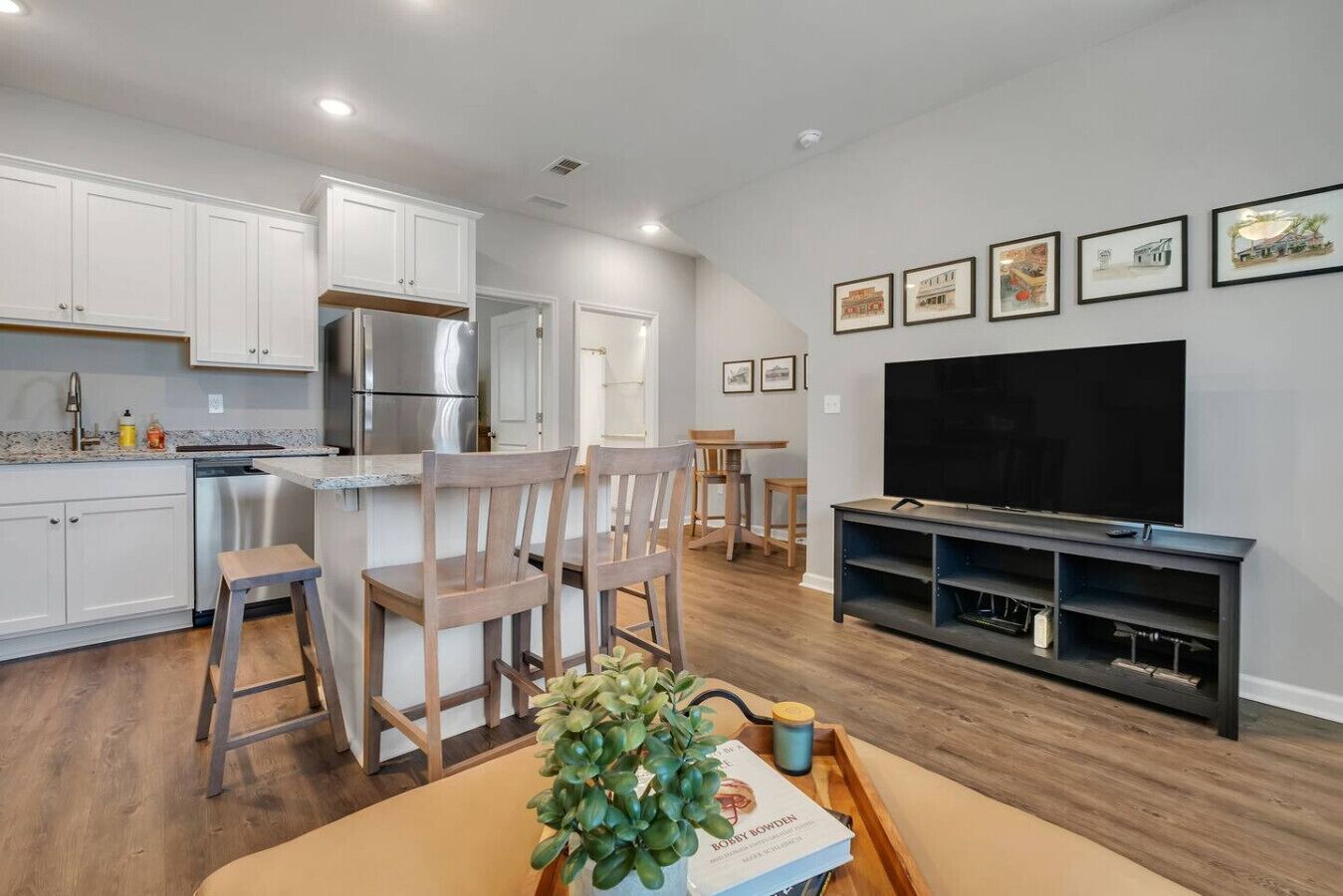 A modern kitchen with white cabinets, stainless steel appliances, and a dining area with wooden chairs and a table.