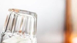 Une assiette blanche sur laquelle repose un verre transparent, le tout posé sur une table en bois.