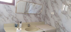 Een badkamer met een marmeren wastafel, een spiegel en een handdoek.