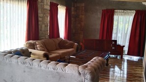 Ein Wohnzimmer mit einem beigen Sofa, einem Holztisch und einem roten Vorhang.