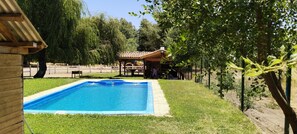 A rectangular swimming pool with a tiled deck, surrounded by grass and trees. - Large house with "private" swimming pool Quincho and river. (Los Angeles)