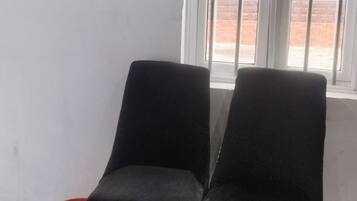 Two black chairs with wooden legs in a room with a window and a red basket on the floor.