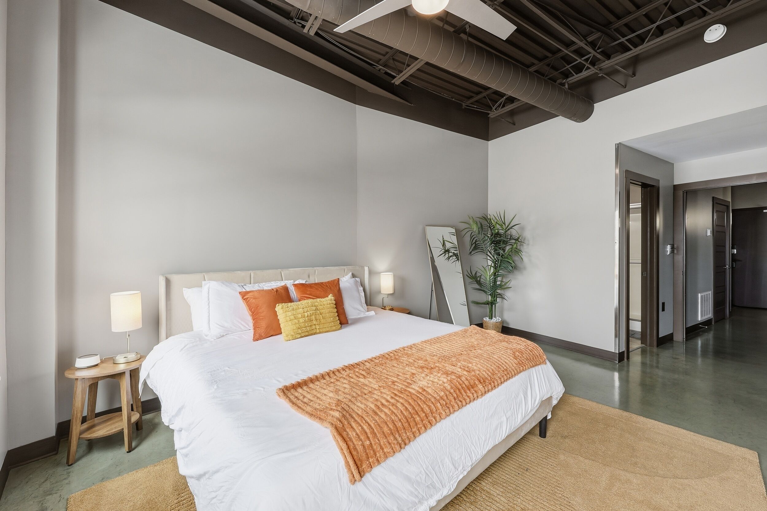 Une chambre d’hôtel moderne avec un grand lit, une table de chevet avec une lampe et une plante.