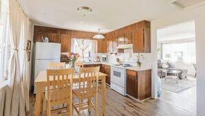 Une cuisine moderne avec des meubles en bois, un réfrigérateur blanc, une cuisinière et un coin repas comprenant une table et des chaises.