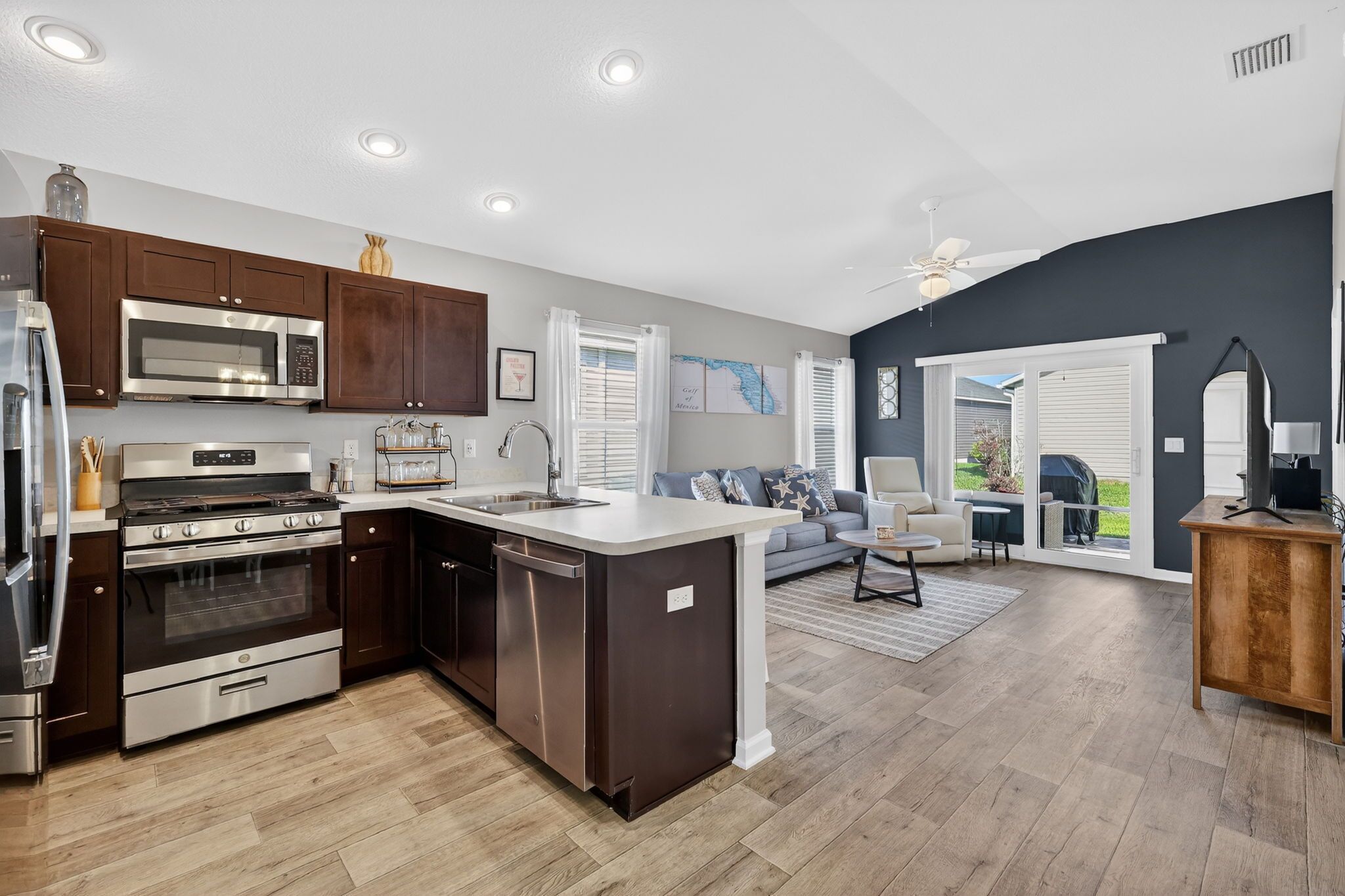 A modern kitchen with dark wood cabinets, stainless steel appliances, and a large island.