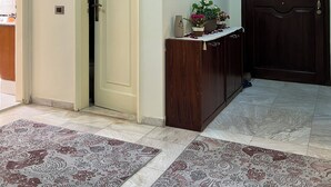 Um corredor com uma porta de cor clara, uma porta de madeira escura e uma pequena mesa com um vaso e plantas.