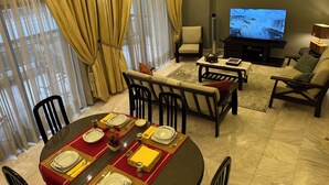 Uma sala de estar com área de jantar, televisão e sofá.