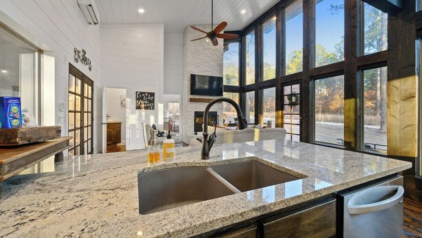 A spacious kitchen with a large granite countertop, a built-in sink, and a ceiling fan. - Luxury Farmhouse Cabin-3 King Suites + Bunk/Game (Broken Bow)