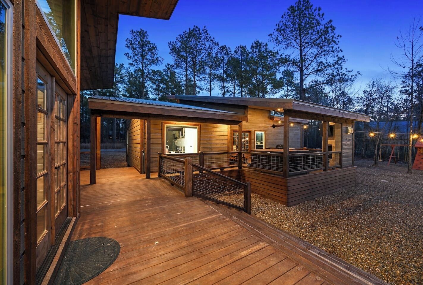 A wooden deck leading to a cabin with a glass door, surrounded by trees.