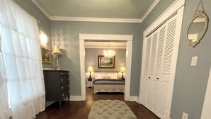 A bedroom with a bed, nightstands, a dresser, a bench, a chandelier, and a closet. - Aggie House near ASU (Jonesboro)