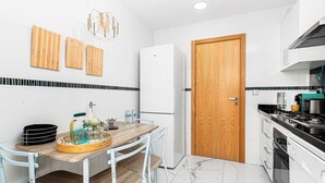 A modern kitchen with white cabinetry, a wooden door, a dining table with chairs, and a black and white tiled backsplash. - Luxury Pool View 3-bedroom, 2 bathrooms, 5-min to Train, Elevator (Tangier)