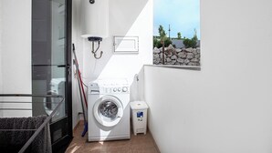 A small laundry room with a washing machine, a trash bin, and a water heater. - Luxury Pool View 3-bedroom, 2 bathrooms, 5-min to Train, Elevator (Tangier)