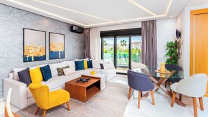 A modern living room with a white sofa, yellow armchair, and a glass dining table with chairs. - Luxury Pool View 3-bedroom, 2 bathrooms, 5-min to Train, Elevator (Tangier)