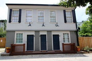A two-story building with a front porch, multiple doors, and a wooden fence. - The Forsyth Victorian Gathering House - Sleeps 19! (Savannah)
