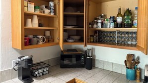 Eine Küche mit Holzschränken, einer Kaffeemaschine, einer Mikrowelle und verschiedenen Küchenutensilien und Gewürzen.