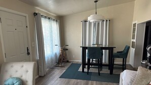 Ein Wohnzimmer mit einer Couch, einem Esstisch mit Stühlen, einem Fahrrad und einer Tür.