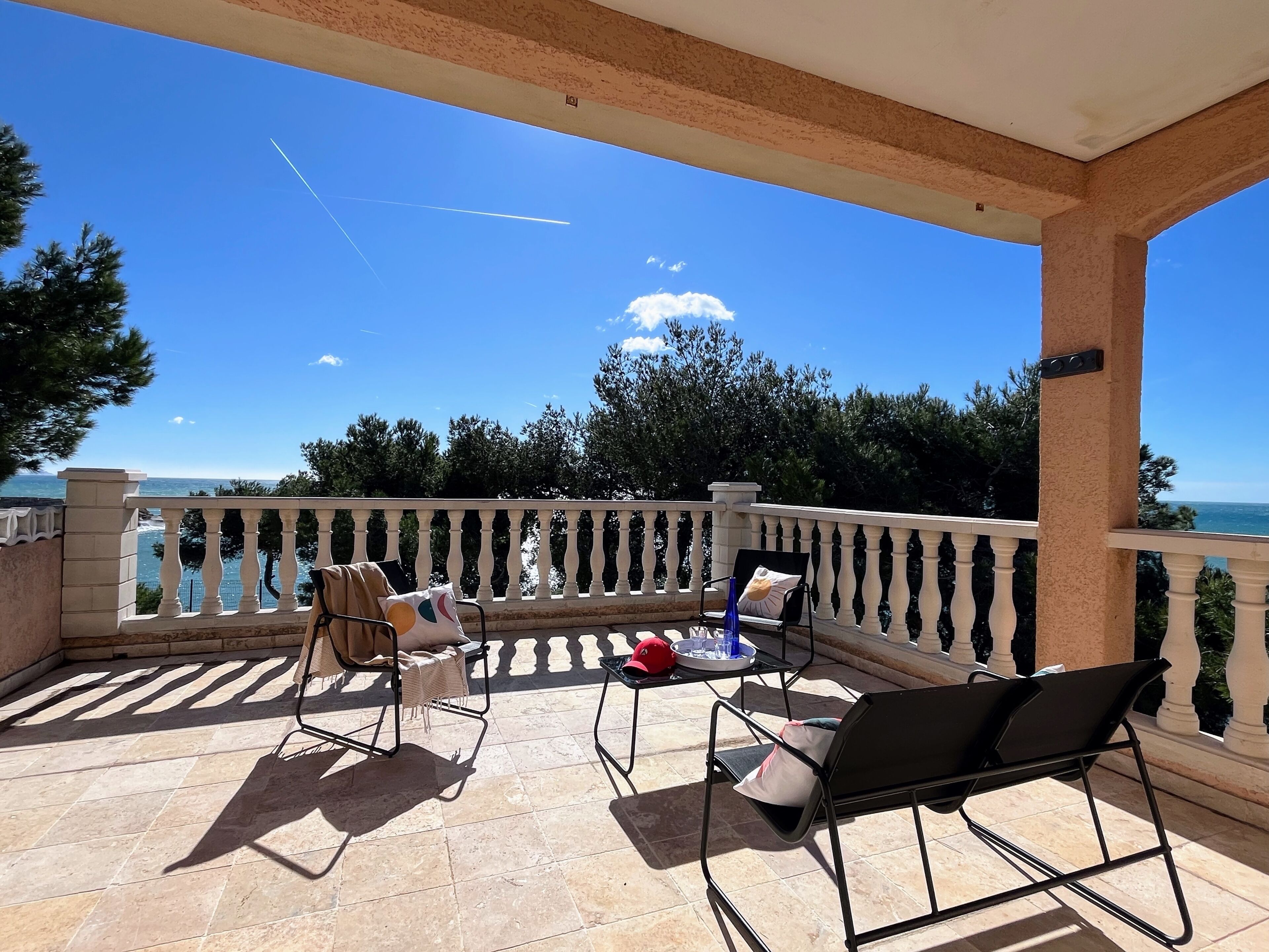 Un balcon avec vue sur la mer, du mobilier d’extérieur et un sol carrelé.