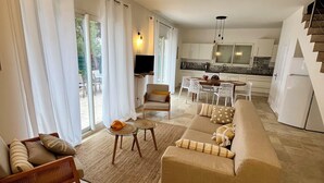 A spacious living area with a sofa, chairs, a small table, and a kitchen in the background. - Seafront villa La Quiétude (Martigues)