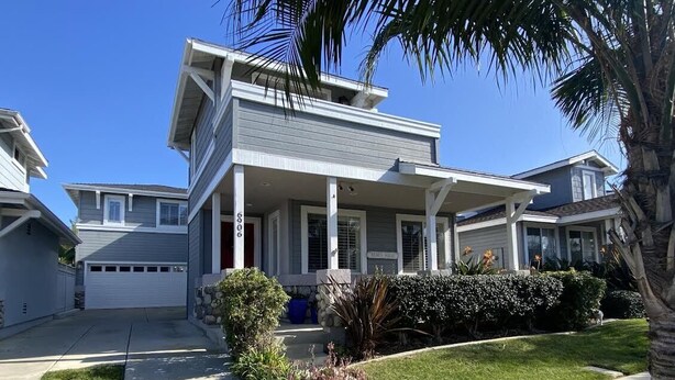 A modern two-story house with a covered porch, a garage, and a well-maintained lawn. - Lovely 3-bedroom w/office  beach house in gate-guarded community (Carlsbad)