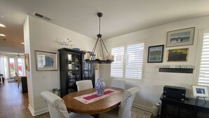 A dining area with a round wooden table, striped chairs, a vase, and a cabinet with dishes. - Lovely 3-bedroom w/office  beach house in gate-guarded community (Carlsbad)