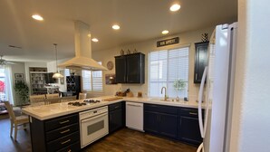 A modern kitchen with dark cabinetry, a white island, and a built-in oven. - Lovely 3-bedroom w/office  beach house in gate-guarded community (Carlsbad)
