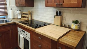 Cozinha moderna com armários de madeira, fogão preto e painel de azulejos branco.