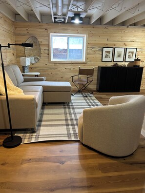 Une pièce confortable avec un canapé, un fauteuil et une petite table sur laquelle se trouve une lampe.