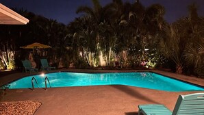 A swimming pool with a tiled deck, surrounded by palm trees and lounge chairs. - Luxe Heated Pool Oasis, 5 Min to Gulf Beaches, Movie Room (Seminole)