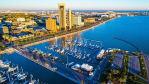 Vista aérea de un puerto deportivo con numerosas embarcaciones amarradas, rodeado de edificios urbanos y una extensa masa de agua.