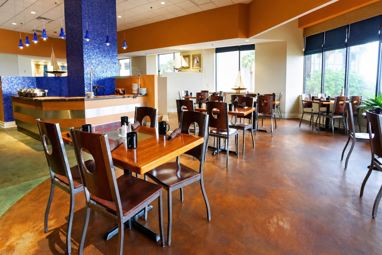 Un restaurant spacieux avec un comptoir central, de nombreuses tables et des chaises.