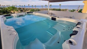 Ein Whirlpool mit freiem Blick auf das Meer und Palmen im Hintergrund.