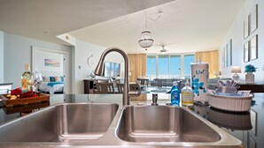 Een moderne keuken met roestvrijstalen spoelbakken, een kroonluchter en een eetgedeelte met uitzicht.