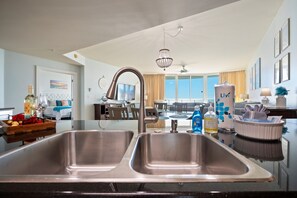 Una cocina moderna con lavamanos de acero inoxidable, una araña y un comedor con vistas.