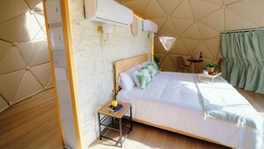 A bedroom with a bed, bedside table, and a small table with a plant.